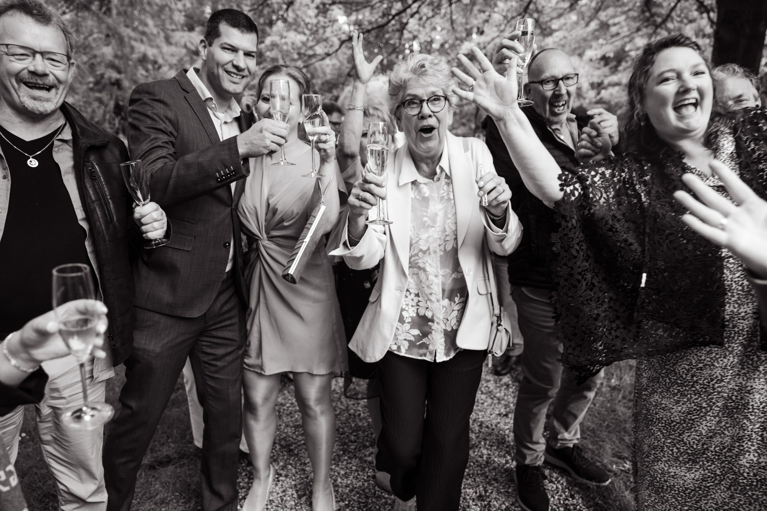 Groep vrienden en familie proostend tijdens een feestelijke bijeenkomst, lachend en genietend van het moment